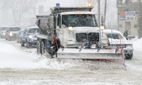 A snow plow clears off the streets for drivers to continue on the roads as snowy conditions continue. 
