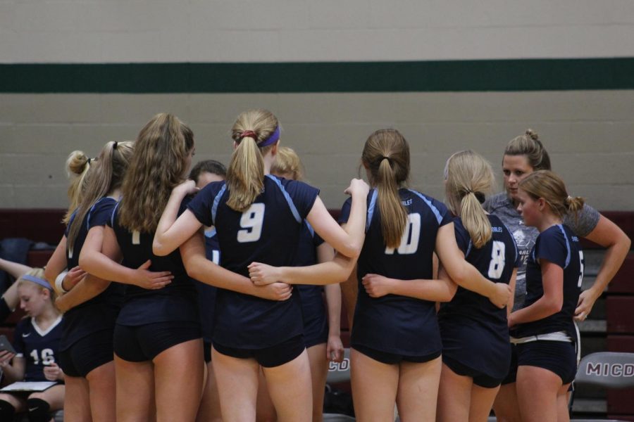 The girls varsity volleyball team huddles before their game on Sept. 10