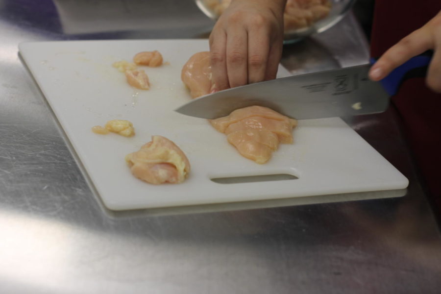 A student cutting chicken