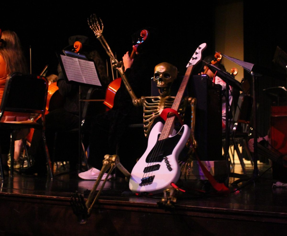 The skeleton, Bobby Bones holds guitar.