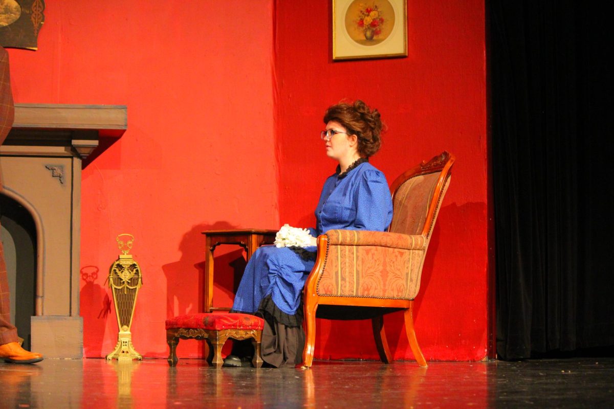 Lady Edwina(Piper Ruebling) sits as she speaks with Sherlock Holmes about the contents of the letters. 