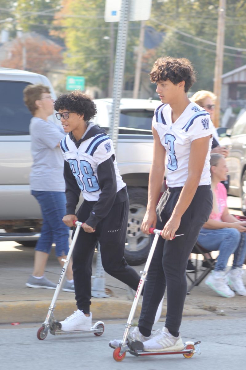 Gabe Young and Ryan Hayes riding scooters at the parade