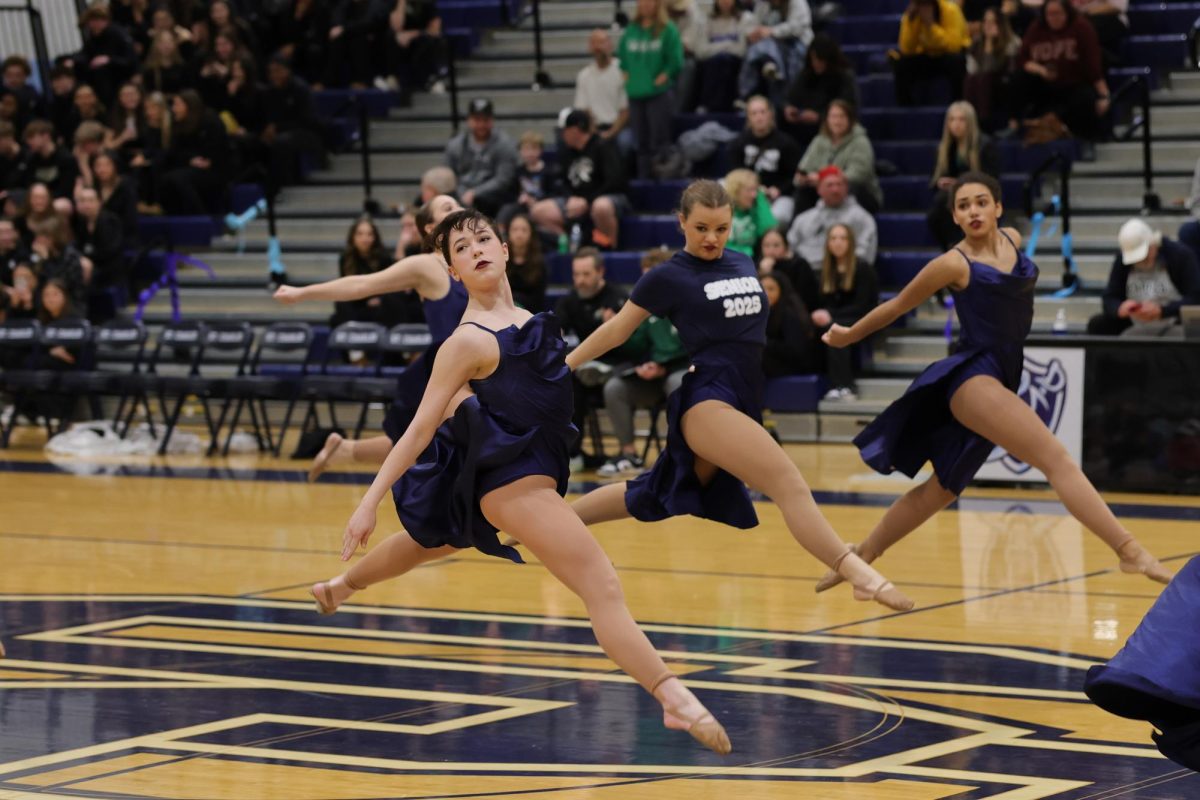 Emma Price. Alex Johns, and Izzy Lathan leaping across the court