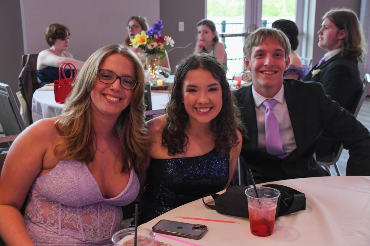 Kenzie Gosa, Colleen Ney, and Tyler Schnatmeier smiling for a photo at prom.