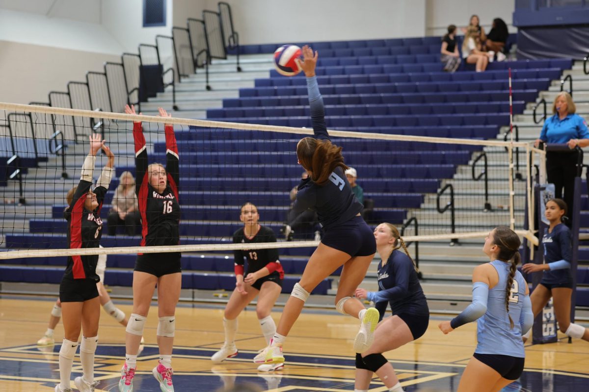 Grace Basler hitting the ball past the other team's blockers
