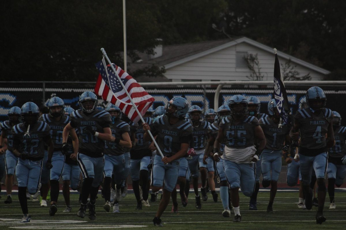 Zeek Lopez carries the flag and runs onto the field with his team.