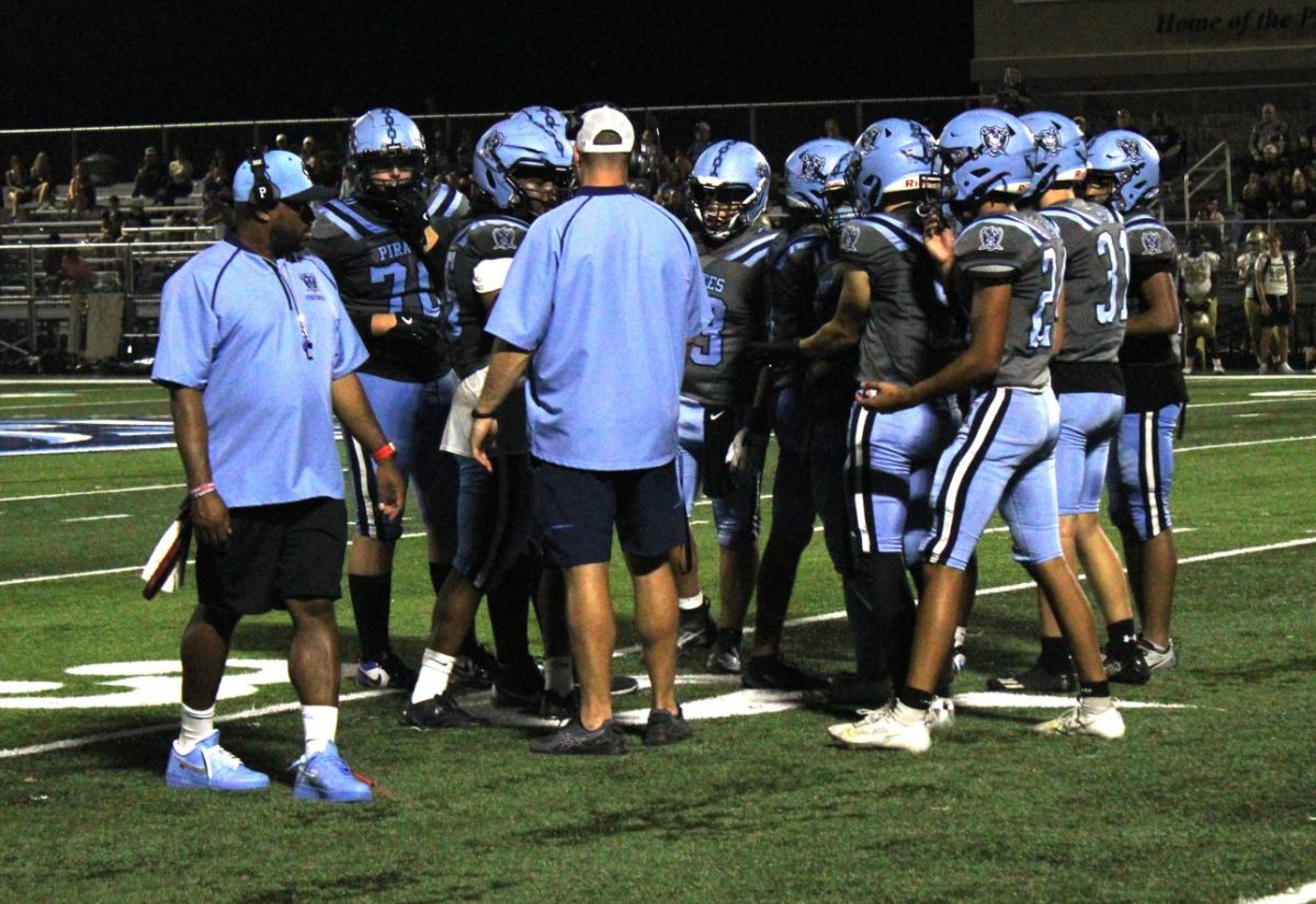 Head Coach McMullen strategizing with the Pirates in the huddle.