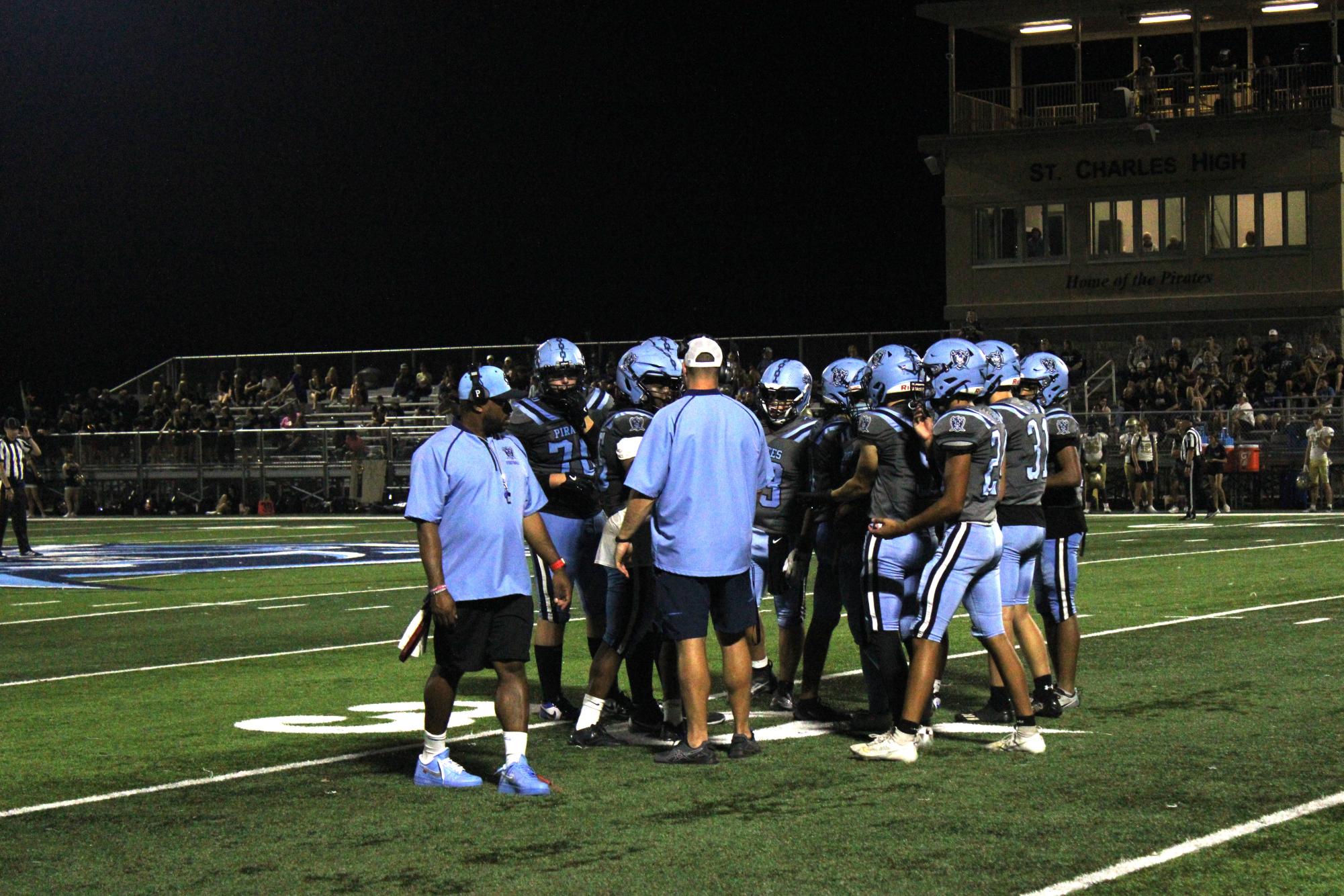 Head Coach McMullen strategizing with the Pirates in the huddle.