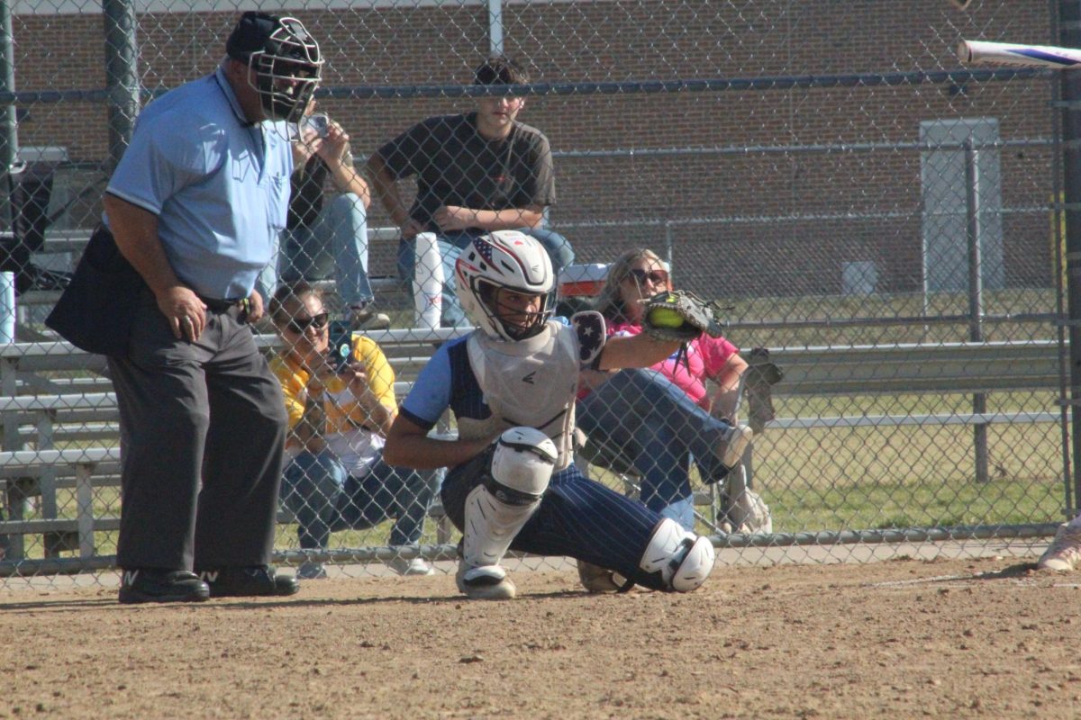 The catcher holds the ball in her glove.