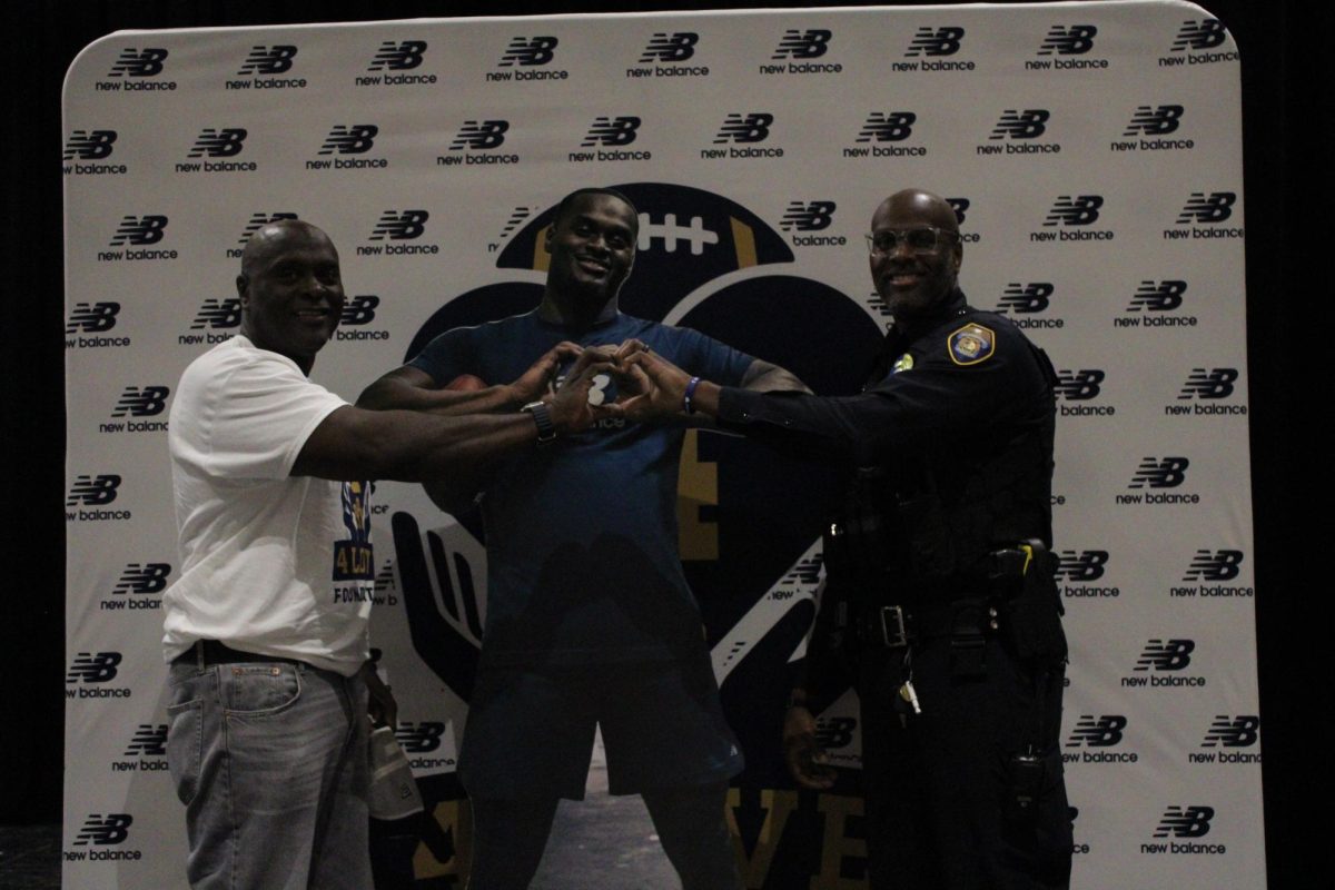 Mr. Love and School Resource Officer Jason Love pose in front of the media backdrop together.