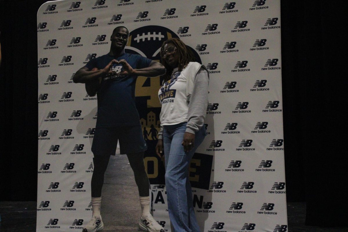 Mrs. Love poses next to a media backdrop of her son.