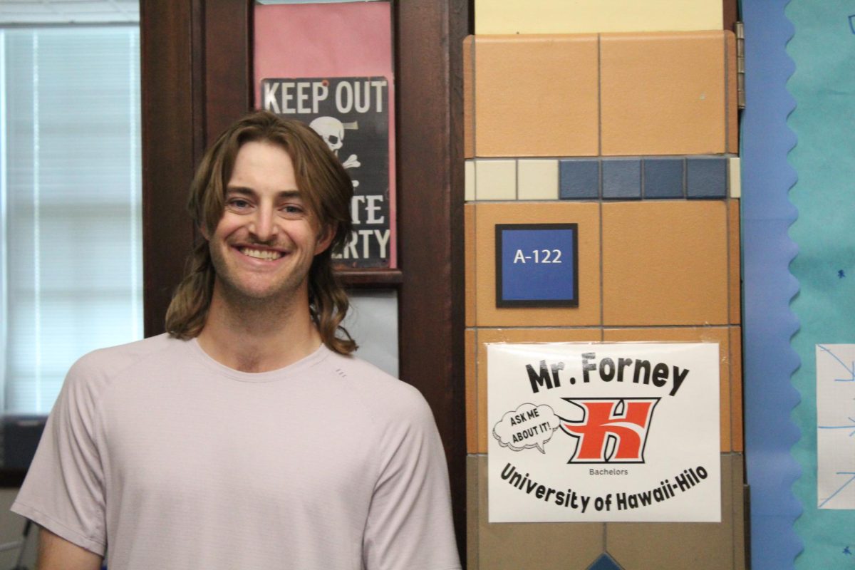 Math teacher Austin Forney standing next to his sign University of Hawaii-Hilo
