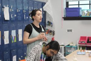 Christine Hilburn helping a student with their art project.